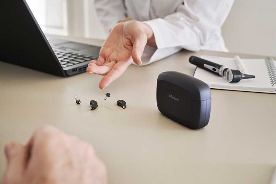 Audiologist demonstrating hearing aids to a patient with hearing loss