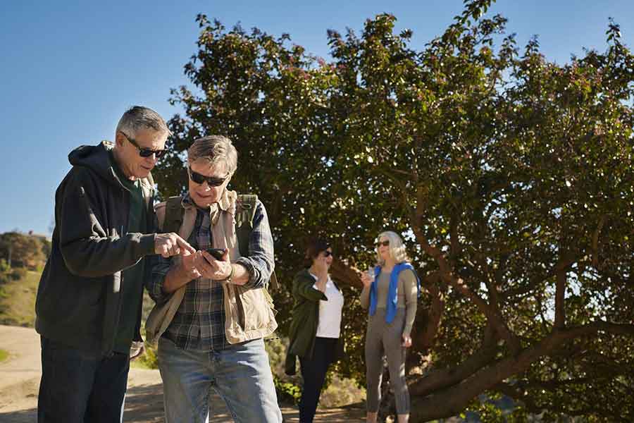 couple using the Beltone SmartRemote app for their hearing aids while hiking