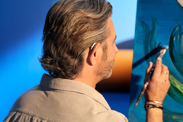 A man painting while wearing a Beltone Envision hearing aid